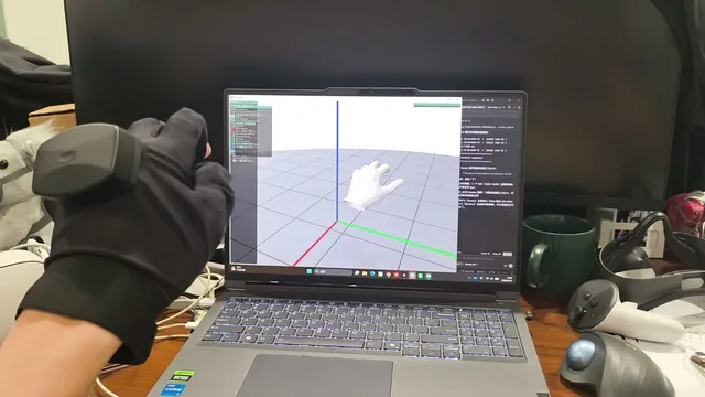 Glovity glove on a desk, with the captured hand pose mirrored by a 3D hand model on a laptop.